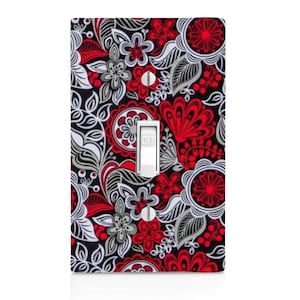 May include: A decorative light switch cover featuring a floral pattern in red, white, and gray on a black background. The switch is white, with the word "OFF" visible. The design includes stylized flowers and leaves.