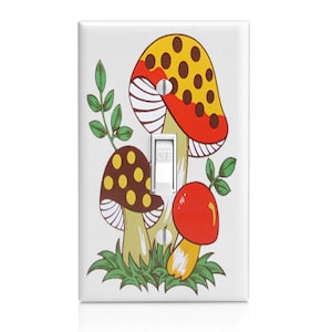 May include: A white light switch cover with a retro design featuring three colorful mushrooms with yellow, red, and brown accents. The mushrooms have white polka dots and are surrounded by green leaves.