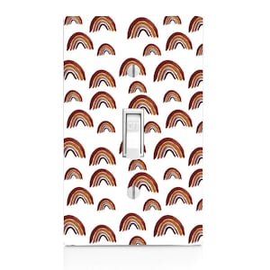 Puede incluir: Una cubierta de interruptor de luz blanca con un patrón de arcoíris marrones, naranjas y morados. El interruptor está etiquetado como "OFF".