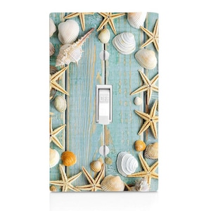 May include: Light switch cover with a beach theme. The cover features a blue and white wooden background with seashells and starfish.