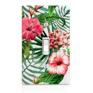 May include: A light switch cover with a tropical floral design featuring pink hibiscus flowers, green leaves, and a white background.