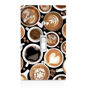 May include: A black light switch cover with a pattern of various coffee cups with different latte art designs. The cups are white with brown coffee and cream. The switch is labeled "OFF".