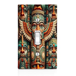 May include: A rectangular light switch plate cover featuring a detailed, colorful pattern of multiple totem pole faces in shades of orange, teal, and cream. The design includes a central toggle switch in white with the word OFF printed on it.
