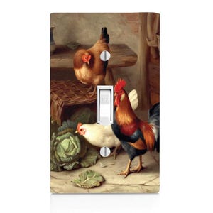 May include: A light switch cover featuring a vintage painting of a rooster and two hens in a rustic setting. The rooster is red, black, and yellow, and the hens are brown and white. The painting is set against a backdrop of a wooden fence and a basket.