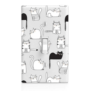 May include: A light switch cover with a white background and a repeating pattern of black and white cats. The switch is labeled "OFF".
