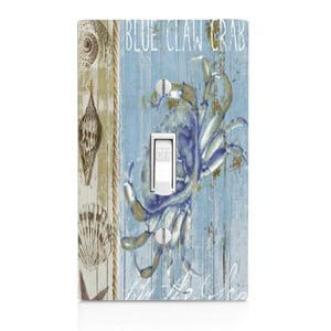 May include: A decorative light switch cover featuring a blue crab design with the text "BLUE CLAW CRAB" on a blue wooden background. The cover also includes seashell and rope accents, and a white switch in the "OFF" position.