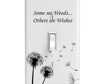 May include: A white rectangular light switch cover plate featuring a black graphic of two dandelion seed heads and floating seeds. The text "Some see Weeds... Others see Wishes" is printed in black script above the central toggle switch.