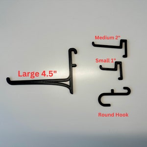 May include: Black 3D-printed display hooks in various sizes. The image shows a large hook at 4.5 inches, a medium hook at 2 inches, a small hook at 1 inch, and a round hook. The text labels each hook's size.