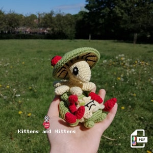 May include: A crocheted plush toy of a green and yellow mushroom-like creature with red accents. The toy is being held in a person's hand. The toy is labeled "Mittens and Kittens" and "PDF".