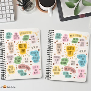 May include: Two white spiral bound notebooks with colorful motivational quotes and illustrations. The notebooks feature positive affirmations such as "You are enough", "You deserve to feel joy", "Good things are coming", "You are worthy", "Think happy thoughts", and "Let your light shine".