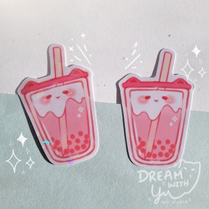 May include: Two pink and white bubble tea stickers with a cute cartoon face and a straw. The stickers have a holographic finish and are surrounded by white stars. The text "DREAM WITH yu" is at the bottom of the image.