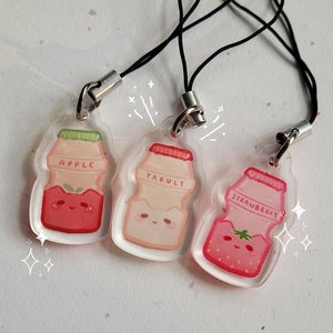 May include: Three clear plastic charms shaped like yogurt bottles with different flavors: apple, yakult, and strawberry. Each charm has a cute cartoon face and is attached to a black string.