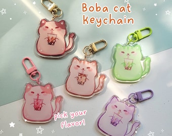 May include: Four colorful boba cat keychains with different colored boba drinks. The keychains are made of clear acrylic and feature a cartoon cat holding a boba drink. The text "Boba cat keychain" and "Pick your flavor!" are printed on the image.