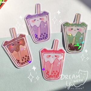 May include: Four colourful holographic stickers of cartoon bubble tea cups with cute faces and straws. The stickers are on a light blue background with white stars.