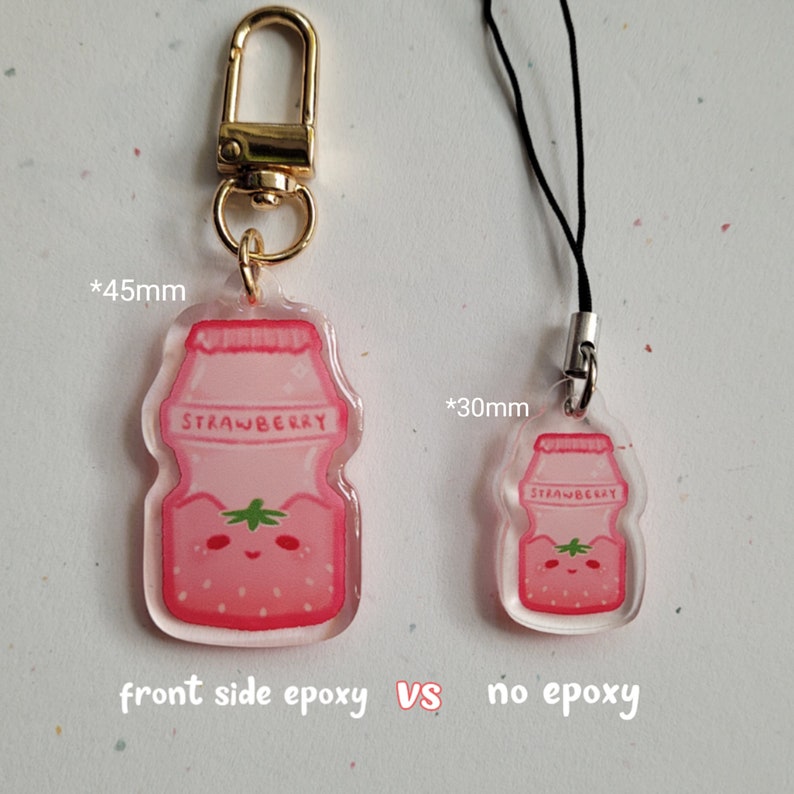 May include: Two pink strawberry yogurt bottle charms, one with a clear epoxy coating on the front and one without. The charm with epoxy is 45 mm tall and the charm without epoxy is 30 mm tall.