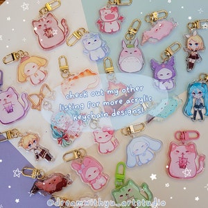 May include: A collection of colorful acrylic keychains featuring various characters, including anime characters, animals, and cartoon figures. The keychains are displayed on a light pink and white background. The text "check out my other listing for more acrylic keychain designs!" is written in black text on a white background.