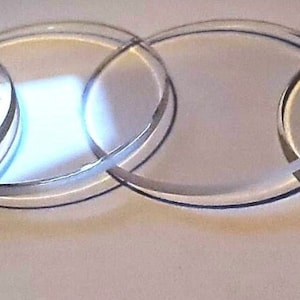 May include: Four clear glass circles of varying sizes, stacked on top of each other.