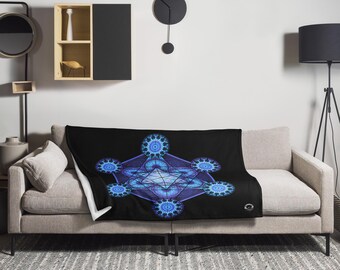 May include: Black throw blanket with a geometric design in shades of blue and purple. The blanket is draped over a beige sofa. The design features a central star shape surrounded by circular patterns.