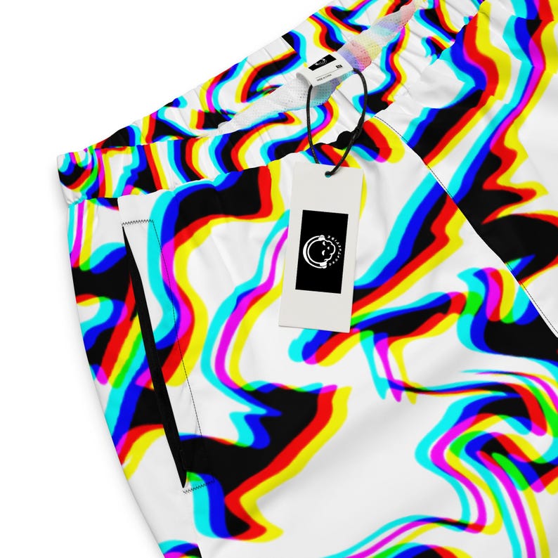 May include: White athletic shorts with a vibrant, abstract pattern in red, yellow, blue, and black. The shorts have a drawstring waistband and a tag with a circular logo. The design creates a colorful, psychedelic effect.
