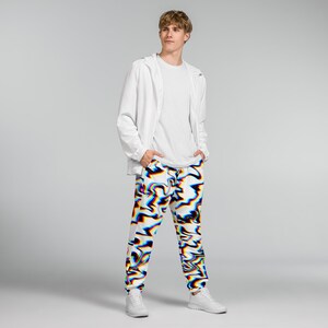 May include: White sweatpants with a colorful, abstract design in red, blue, and black. The pants have a drawstring waist and elastic cuffs. The person is wearing a white jacket and t-shirt.
