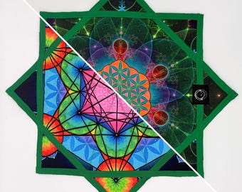 May include: A colorful, geometric patterned textile with a green border. The design features vibrant hues of blue, pink, orange, and green, with intricate patterns and shapes. A small black tag with a white symbol is in the corner.
