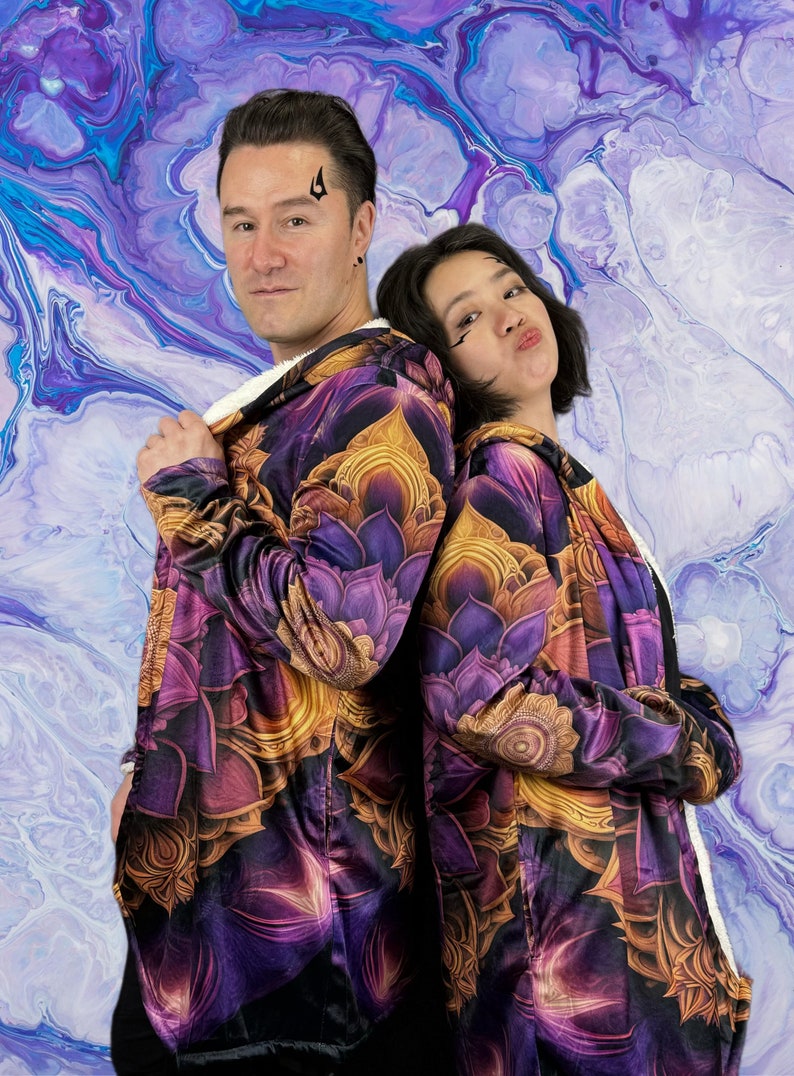 May include: Two people wearing purple and gold hooded jackets with a floral pattern. The jackets have a sherpa lining. The background is a blue and purple abstract painting.