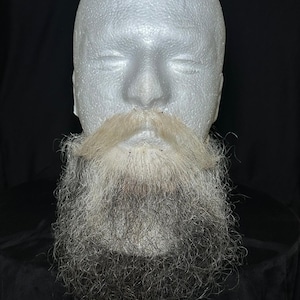Puede incluir: Una cabeza de maniquí blanca con una barba larga, gris y blanca y un bigote marrón claro.
