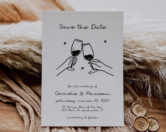 Może przedstawiać: Karta Save the Date z minimalistycznym wzorem przedstawiającym dwa kieliszki wina, które się zderzają. Tekst brzmi "Save the Date" na ślub Cornélie & Marceau, sobota, 23 marca 2027, St. Mary's Star of the Sea, 145 Main St., Unionville, CT, zaproszenia do nadejścia.