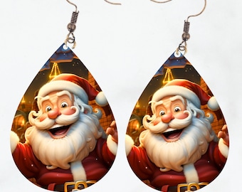 May include: A pair of teardrop-shaped earrings featuring a smiling Santa Claus with a white beard and red suit. The background shows a festive scene with lights and buildings. The earrings have silver-colored fish hook ear wires.
