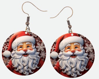May include: A pair of round Christmas earrings featuring Santa Claus. Each earring has a red Santa hat, a white beard, and a smiling face. The background is a dark red with white snowflakes. The earrings hang from silver-colored hooks.