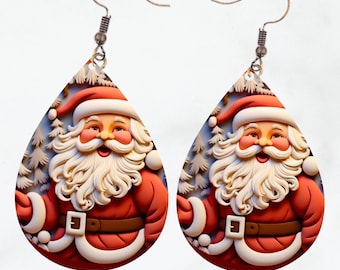 May include: A pair of Christmas-themed earrings featuring a Santa Claus design. The earrings are teardrop-shaped with a red and white color scheme, depicting Santa's face, beard, and suit. The background includes white trees. The earrings have silver-colored hooks.
