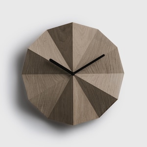 Könnte beinhalten: Eine braune Wanduhr aus Holz mit schwarzen Zeigern und einem geometrischen Design. Das Zifferblatt der Uhr besteht aus mehreren Holzstücken, die radial angeordnet sind.
