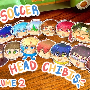 May include: A collection of colorful anime-style head stickers. The stickers feature various characters with different hair colors and expressions. The word "SOCCER" is at the top, and "HEAD CHIBIS VOLUME 2" is at the bottom.
