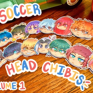 May include: A set of 12 colorful cartoon character head stickers with the text "Soccer Head Chibis Volume 1".