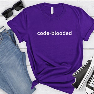 a purple t - shirt that says code - blooded next to a pair of
