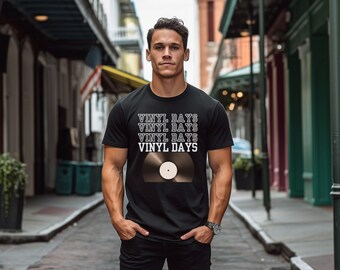 Op de afbeelding: Een zwart T-shirt met een witte afbeelding van een vinylplaat en de tekst "Vinyl Days" die vier keer wordt herhaald.