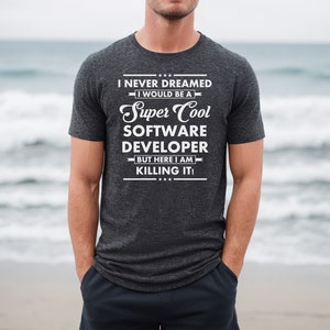 May include: A dark grey t-shirt with white text that reads "I never dreamed I would be a Super Cool Software Developer but here I am killing it!"
