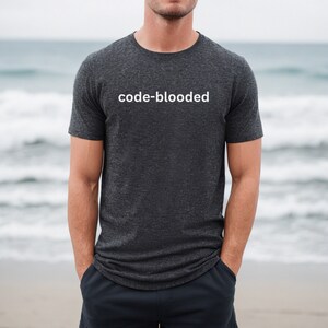 a man is standing on the beach wearing a t - shirt that says code -