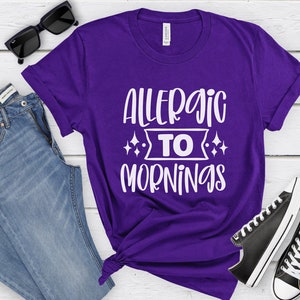 May include: Purple t-shirt with white text that reads "Allergic to Mornings".