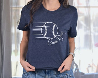 May include: A navy blue t-shirt with a white baseball graphic and the text "Game Day" in a cursive font.