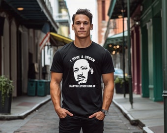 Może przedstawiać: Czarny T-shirt z białym nadrukiem przedstawiającym Martina Luthera Kinga Jr. i tekstem "I Have A Dream" oraz "Martin Luther King Jr."