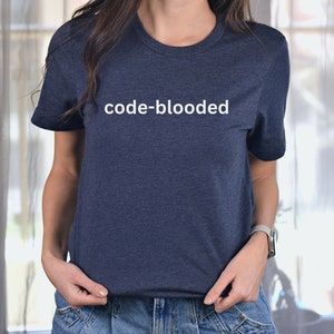 a woman standing in front of a window wearing a t - shirt that says code