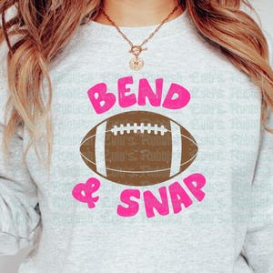 May include: A gray sweatshirt with the text "Bend & Snap" in pink lettering and a brown football graphic.