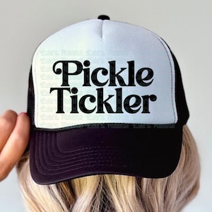 May include: A black and white trucker hat with the text "Pickle Tickler" in bold, black letters. The hat has a white front panel and a black mesh back. The brim is black.