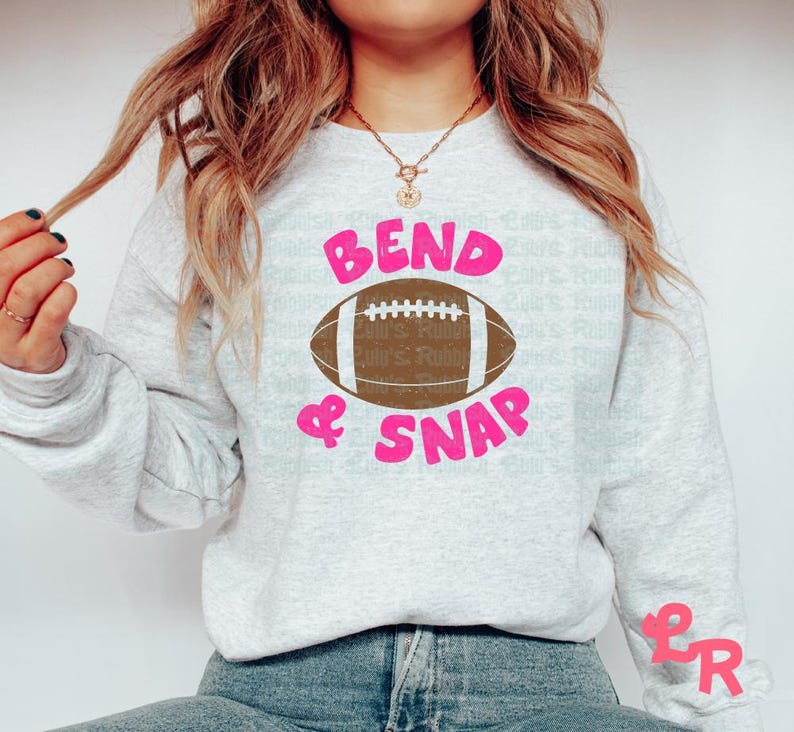 May include: A gray sweatshirt with the text "Bend & Snap" in pink lettering and a brown football graphic.