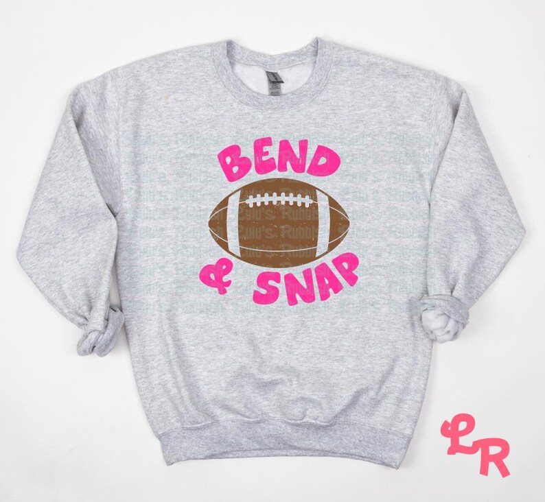May include: Gray sweatshirt with a pink graphic of a football and the text "Bend & Snap".