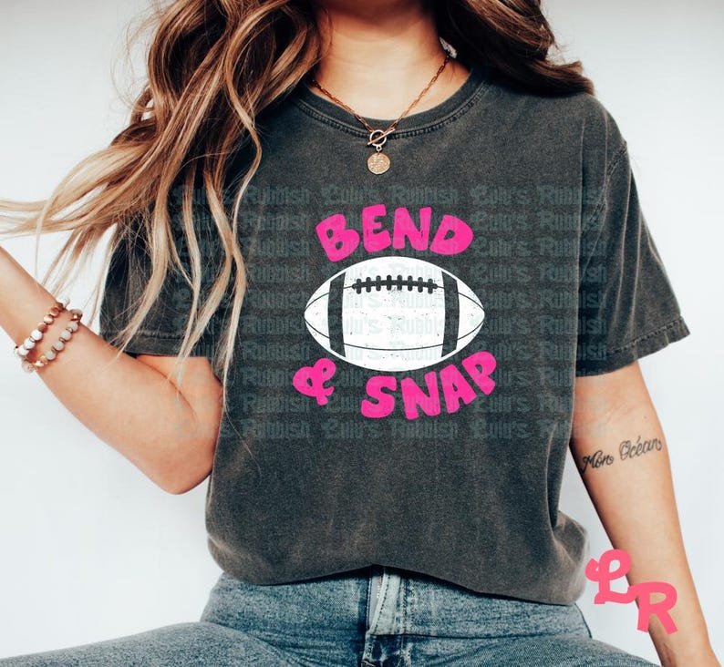 May include: A dark gray t-shirt with the text "Bend & Snap" in pink letters and a white football graphic.