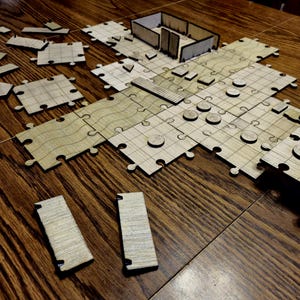 May include: A wooden jigsaw puzzle with a variety of shapes and sizes. The puzzle is made up of individual pieces that fit together to create a larger image. The pieces are all made of light brown wood and have a smooth finish.