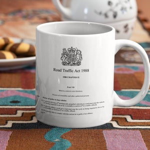 May include: White ceramic mug with a black and white image of the British Royal Coat of Arms and the text "Road Traffic Act 1988 1988 Chapter 52 Part VII Miscellaneous and General Powers of constables and other authorised persons Power of police to stop vehicles (1) A person driving a 'mechanically propelled vehicle' on a road must stop the vehicle if he is being required to do so by a constable (or a traffic officer). (2) A person riding a cycle on a road must stop the cycle on being required to do so by a constable (or a traffic officer). (3) A person required to do so by a constable in uniform (or a traffic officer) must do so by the side of the road, or in a traffic control area. (4) If a person fails to comply with this section he is guilty of an offence."