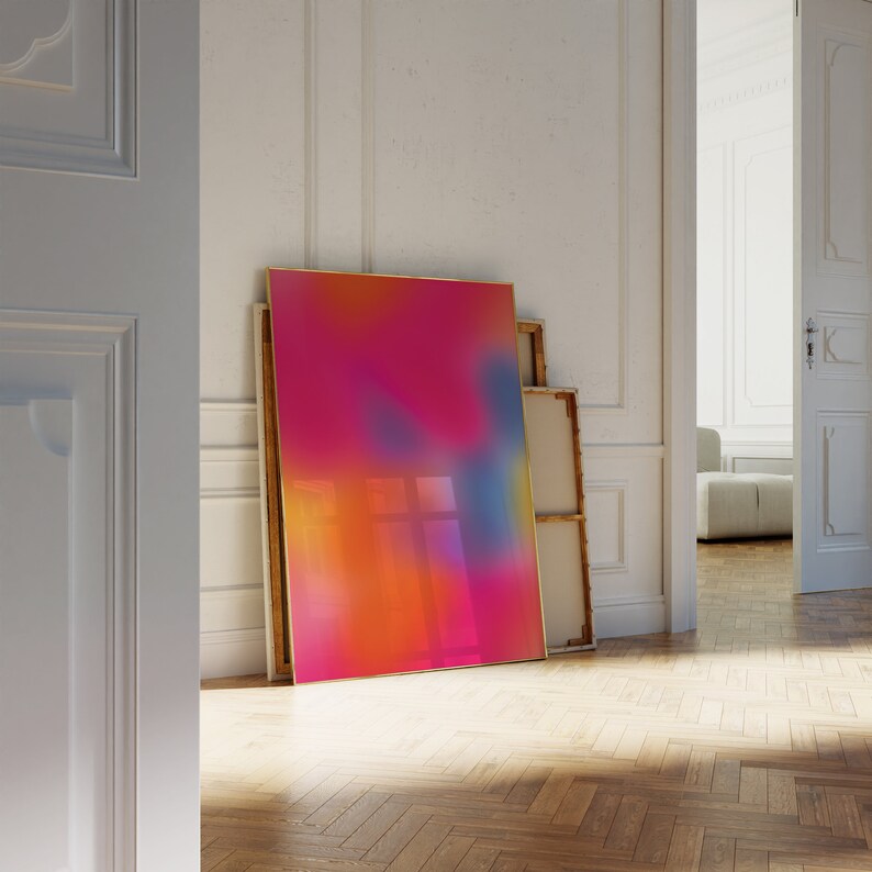 May include: A colorful abstract painting in a gold frame, leaning against a white wall in a room with wooden floors.
